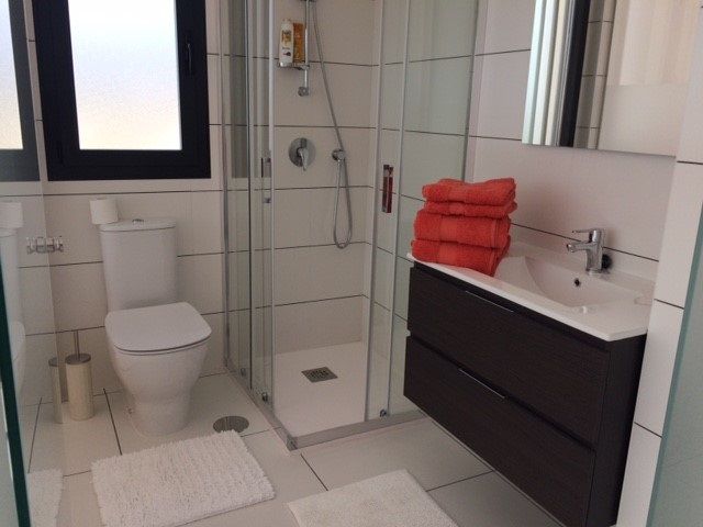 Badrum med dusch tillhörande master bedroom. Här finns gott om förvaring för toalettartiklar i lådorna under handfatet. Ett handduk-set per person för dusch och händer finns att låna. Handdukar för pool och strand ingår inte.